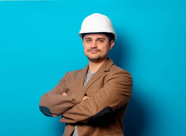 Jovem engenheiro de capacete e jaqueta em fundo azul — Fotografia de Stock