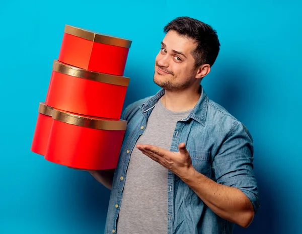 Knappe man met rode geschenken op blauwe achtergrond — Stockfoto