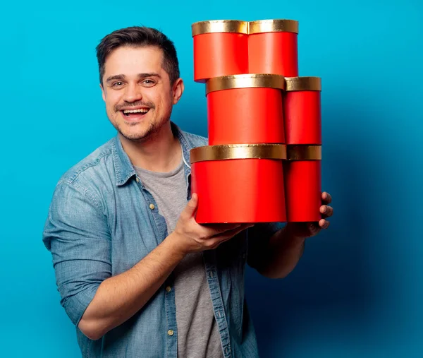 Pohledný muž s červenými dárky na modrém pozadí — Stock fotografie