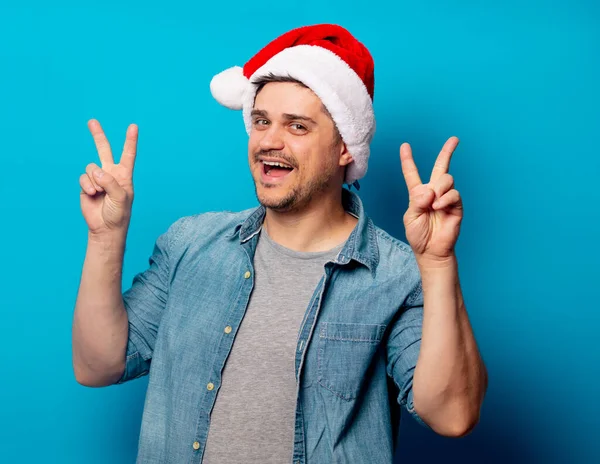 Knappe man met kerstmuts op blauwe achtergrond — Stockfoto