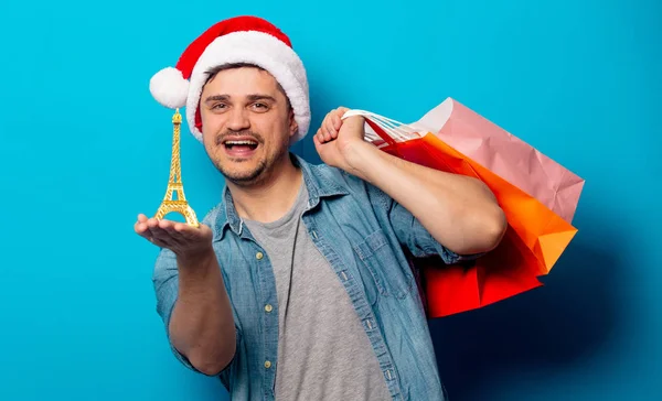 Snygg man i julhatt med shoppingväskor och Eiffel towe — Stockfoto