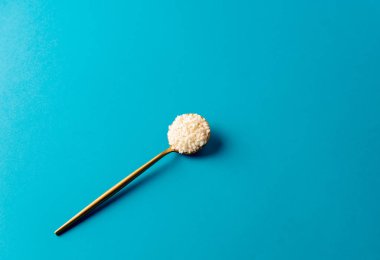 Mavi arka planda pirinç taneleri olan altın kaşık