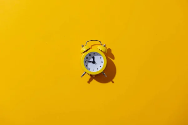 黄色の背景に2つの鐘と目覚まし時計 — ストック写真