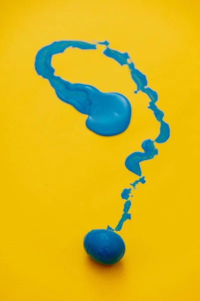 Ovo de Páscoa em tinta azul sobre fundo amarelo — Fotografia de Stock