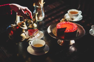 Kadınlar çay partisinde çaylarını çiğ kekle doldurur.