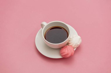 Pembe arka planda krema ve bir fincan kahve.