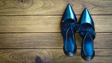 Ahşap arka plan üzerinde siyah yüksek topuk ayakkabı