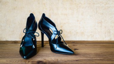 Ahşap arka plan üzerinde siyah yüksek topuk ayakkabı