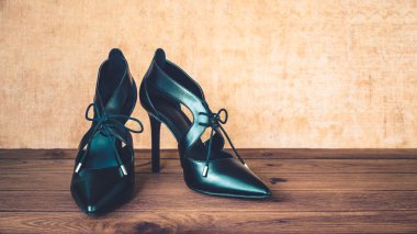 Ahşap arka plan üzerinde siyah yüksek topuk ayakkabı