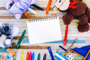 Boya kalemi, oyuncaklar, boş açık defter ile şirin bebek ve