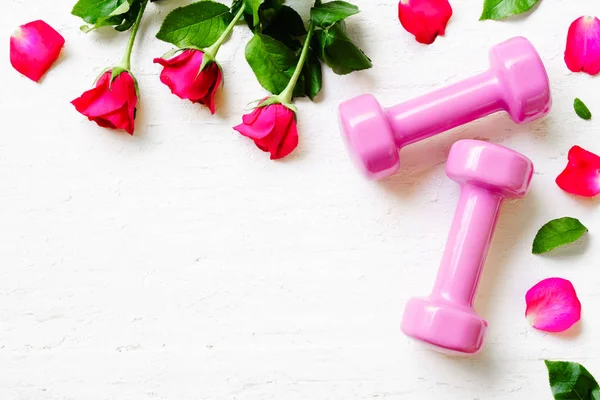 Pembe spor dumbell ve Beyaz ahşap zemin üzerinde kırmızı gül,