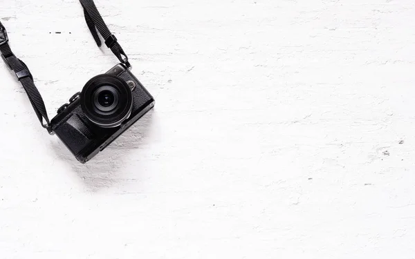 Black camera on the grunge white wooden background. Flat lay of travel accessories Background concept.