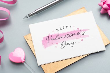 Gri arkaplanda Mutlu Valen ile birlikte sahte kartpostal ve zarf.