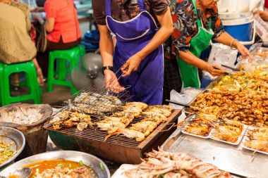 Adam karides ızgara yemek yapıyor.