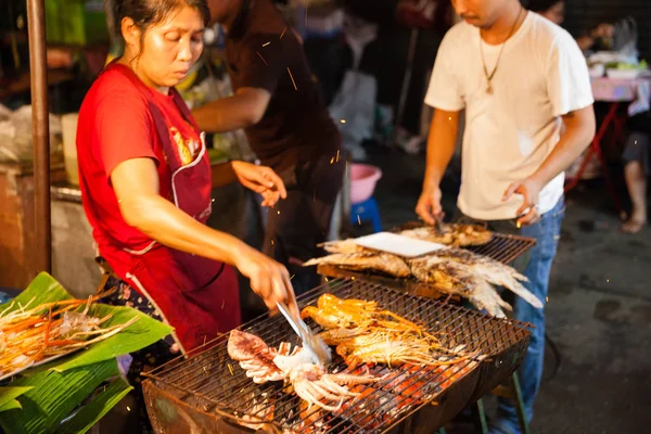 Mujer cocina langostinos y calamares en la parrilla —  Fotos de Stock