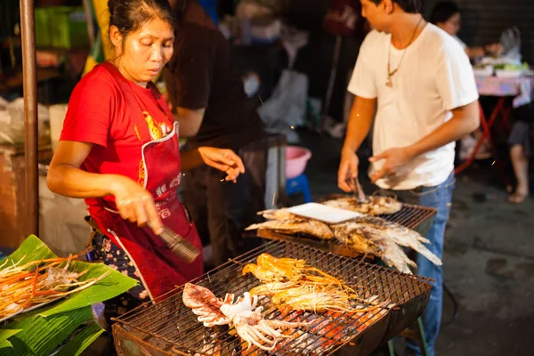 Mujer cocina langostinos y calamares en la parrilla —  Fotos de Stock