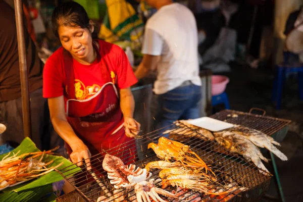 Femme cuisine crevettes et calmars sur le gril — Photo