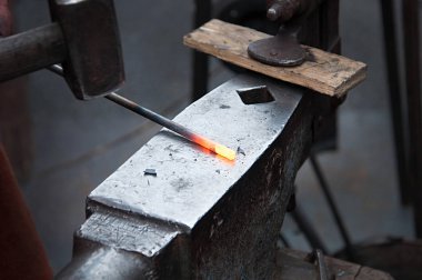 Demirci demircideki erimiş metali elle dövüyor.