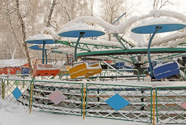 Assentos de carrossel cobertos de neve no parque de diversões no inverno — Fotografia de Stock