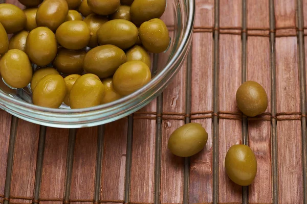 olives in a glass plate on a brown background