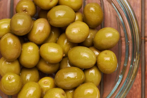 olives in a glass plate on a brown background
