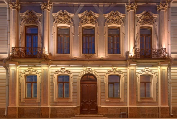 Janelas, portas e varandas na fachada noturna do prédio de apartamentos — Fotografia de Stock