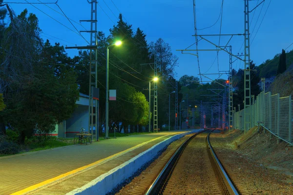 Plataforma de estação ferroviária e ferrovia no crepúsculo — Fotografia de Stock