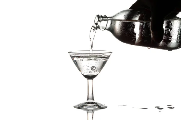 Verser de l'eau ou du soda dans un verre à martini sur fond blanc — Photo