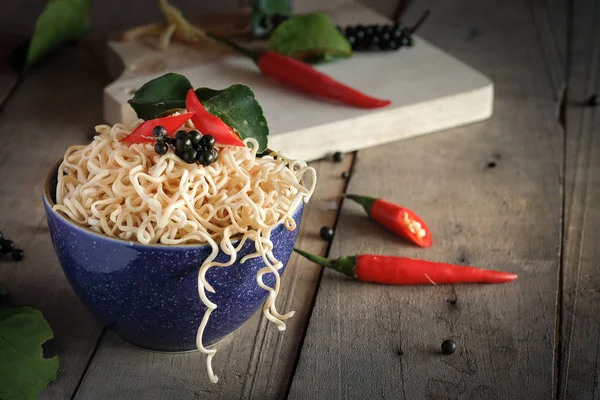 Instant noodles in a bowl with chili pepper and lime leaves — Stock Photo, Image