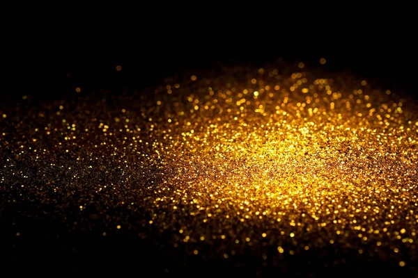 Cospargere polvere glitter oro su uno sfondo nero con spazio copia . — Foto Stock
