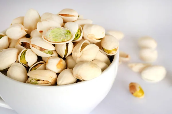 Pistachios are dried in a white cup on a white background. — Stock Photo, Image