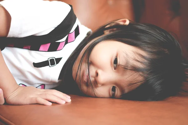 Азиатская девочка в печальном настроении одиноко лежит на диване — стоковое фото
