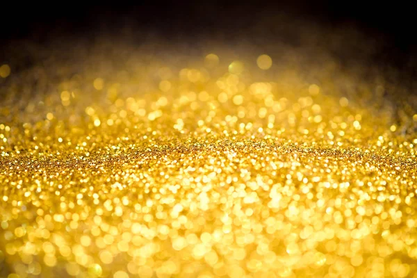 Polvilhe o pó de ouro glitter em um fundo preto, textura de fundo abstrata — Fotografia de Stock