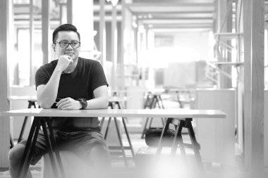 Asyalı erkek masada bir şey düşünüyor oturuyorsun.