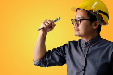 Genç bir mühendis aktif olarak hazır sarı bir arka plan üzerinde çalışmaya davranıyor.