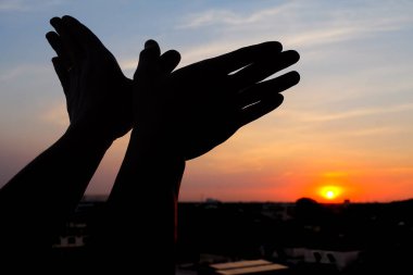 bir arka plan günbatımı üzerinde uçan kuş gibi bir el hareketi silüeti