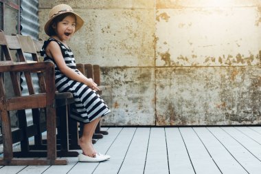 Esneme ve tahta sandalyede oturan Asyalı çocuk kız