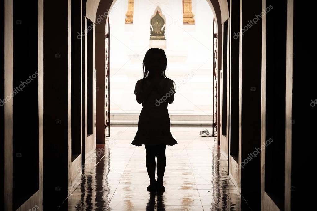 The silhouette of a girl standing pay respect in a temple