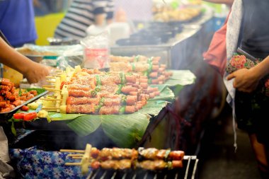 Mangal kömürü ocağında kızartılıyor ve gece pazarında duman yüzüyor..