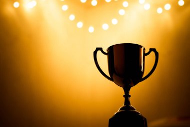 Altın Kupa rekabet içinde belgili tanımlık karanlık ile kopya alanı, muhteşem başarı kavramı soyut bulanık ışık arka plan üzerinde