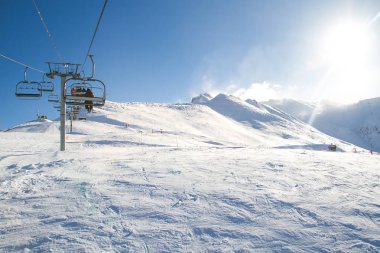 Kış telesiyej, teleferik güneşli bir günde taşımak kayakçılar, güneş karşı arkadan fotoğraf