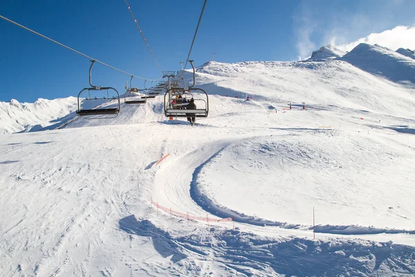 Telesilla, silla, esquí, telesilla que lleva esquiador y snowboarder en un día soleado en invierno — Foto de Stock