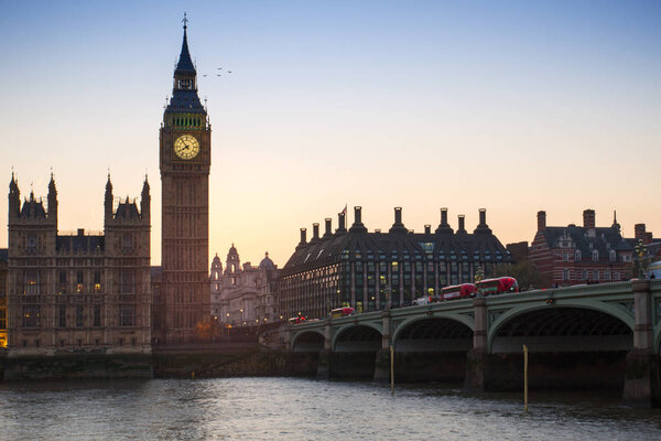 The Big Ben, the Houses of Parliament and Westminster bridge in London in beautiful summer evening at sunset, England, United Kingdom. Double Decker bus, buses in front.