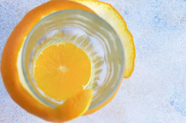 A glass with an orange slice inside and an orange peel on the outside