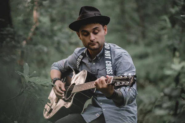 Guy in the woods playing guitar