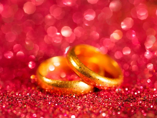 Dva Staré Zlaté Snubní Prsteny Jasně Červeném Rozmazaném Třpytivém Pozadí — Stock fotografie