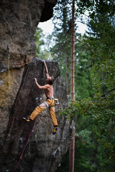 El hombre está escalando en la roca. Subir con éxito, alcanzar la cima Adrenalina, fuerza, ambición . — Foto de Stock