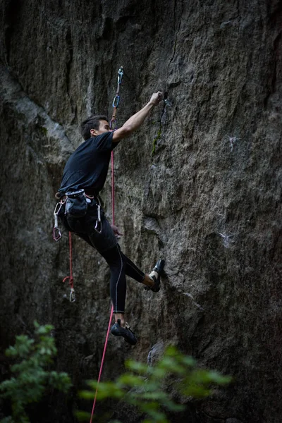 Escalador de rocas cuelga en el aire mientras lucha por escalar un acantilado desafiante . —  Fotos de Stock