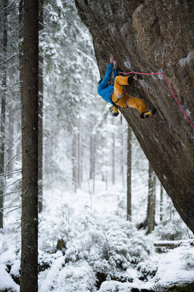 Extreme winter sport. Rock climber climbing in beautiful rocky area. 