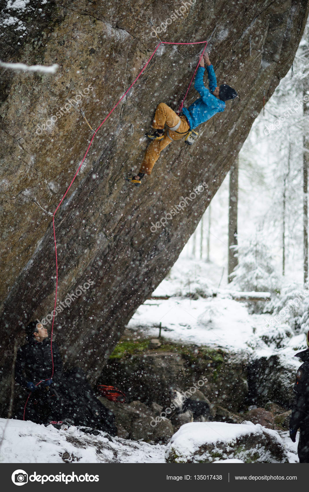 Extreme winter sport climbing. Young male rock climber on a rock wall